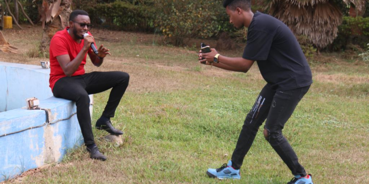 Pacifique Izabayo (R) shoots a video for his team member in Kigali, Rwanda, on Aug. 13, 2022. Rwandan youth, Pacifique Izabayo, has become a hit on Douyin, the Chinese version of TikTok, for singing Chinese songs while showing Rwandan rural life. (Photo by Huang Wanqing/Xinhua)